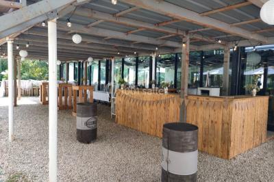 Salle sombre avec éclairage violet, plafond métallique, tables et chaises dispersées sur un sol à carreaux.