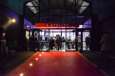 Salle de projection avec des rangées de sièges rouges, un écran noir et un plafond équipé de luminaires.