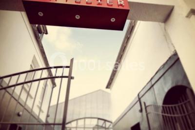 Salle de projection avec des rangées de sièges rouges, un écran noir et un plafond équipé de luminaires.