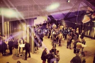 Salle de projection avec des rangées de sièges rouges, un écran noir et un plafond équipé de luminaires.