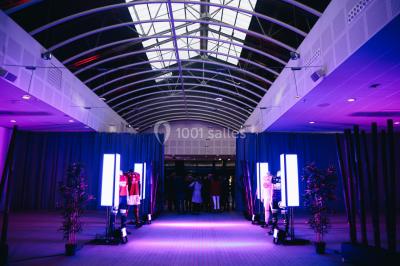 Salle de projection avec des rangées de sièges rouges, un écran noir et un plafond équipé de luminaires.