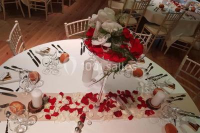 Structure en bois avec décorations de mariage, incluant des lettres blanches, un tonneau et des fleurs suspendues.