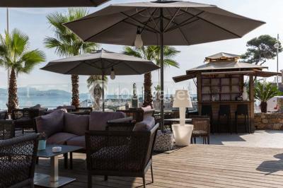 Une femme échange avec une réceptionniste dans le hall lumineux d'un hôtel, avec un coin salon visible en arrière-plan.