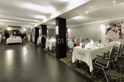 Une femme échange avec une réceptionniste dans le hall lumineux d'un hôtel, avec un coin salon visible en arrière-plan.