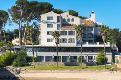 Une femme échange avec une réceptionniste dans le hall lumineux d'un hôtel, avec un coin salon visible en arrière-plan.