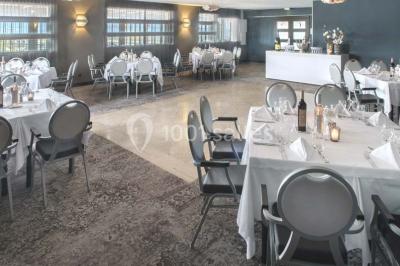 Une femme échange avec une réceptionniste dans le hall lumineux d'un hôtel, avec un coin salon visible en arrière-plan.