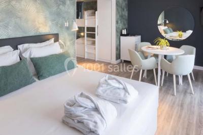 Une femme échange avec une réceptionniste dans le hall lumineux d'un hôtel, avec un coin salon visible en arrière-plan.