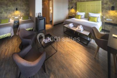 Une femme échange avec une réceptionniste dans le hall lumineux d'un hôtel, avec un coin salon visible en arrière-plan.