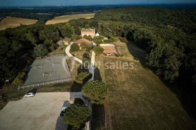 Vue aérienne d'un domaine entouré de forêts et de champs au coucher du soleil, avec des bâtiments et des allées visibles.