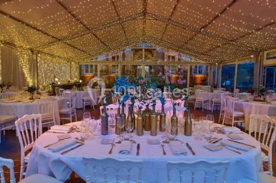 Vue aérienne d'un domaine entouré de forêts et de champs au coucher du soleil, avec des bâtiments et des allées visibles.
