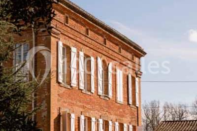 Vue aérienne d'un domaine entouré de forêts et de champs au coucher du soleil, avec des bâtiments et des allées visibles.