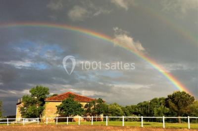 Vue aérienne d'un domaine entouré de forêts et de champs au coucher du soleil, avec des bâtiments et des allées visibles.