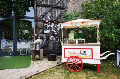 Chemin en gravier menant à des chalets en bois entourés de pelouse et d'arbres sous un ciel dégagé.