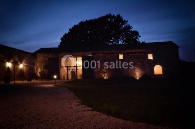 Salle de réception décorée avec des tables dressées, nappes blanches, chaises pliantes et centres de table fleuris.