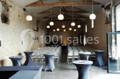 Salle de réception décorée avec des tables dressées, nappes blanches, chaises pliantes et centres de table fleuris.