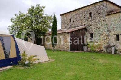Salle de réception décorée avec des tables dressées, nappes blanches, chaises pliantes et centres de table fleuris.