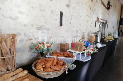 Salle de réception décorée avec des tables dressées, nappes blanches, chaises pliantes et centres de table fleuris.
