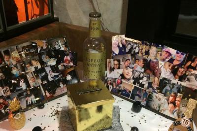 Table de restaurant dressée avec nappes noires et grises, verres, couverts, serviettes pliées et menu au centre.