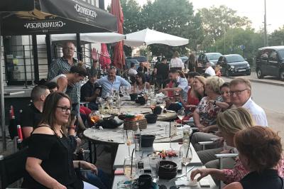 Table de restaurant dressée avec nappes noires et grises, verres, couverts, serviettes pliées et menu au centre.