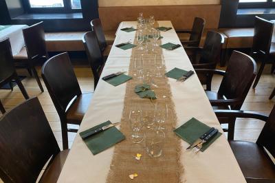 Table de restaurant dressée avec nappes noires et grises, verres, couverts, serviettes pliées et menu au centre.