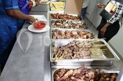 Assiette contenant du riz, du poulet grillé, des bananes plantains frites, des légumes sautés et des sauces en…