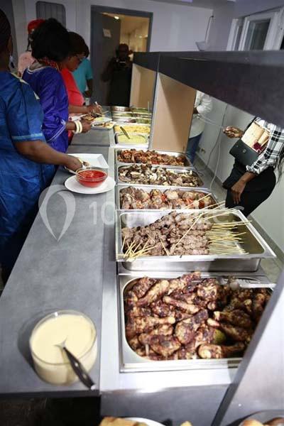 Buffet avec divers plats, incluant brochettes, viandes grillées et sauces, servi sur un comptoir en inox.