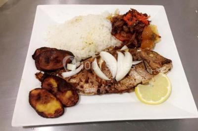 Assiette contenant du riz, poulet grillé, bananes plantains frites, légumes sautés et sauces en accompagnement.