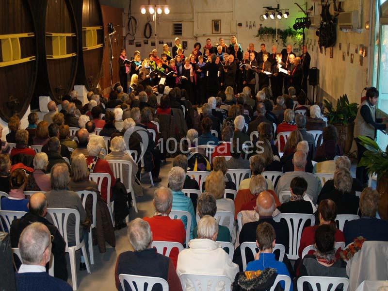 Un chœur chante devant un public assis dans une salle avec des tonneaux en arrière-plan.