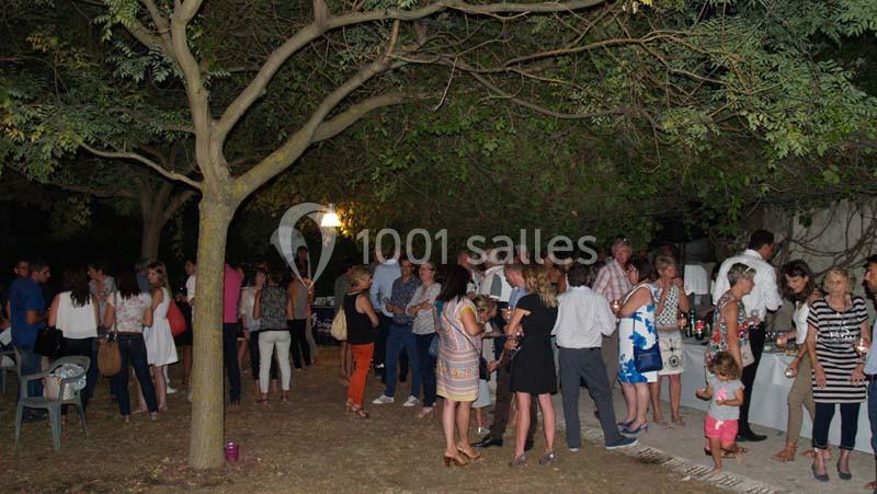 Groupe de personnes rassemblées en soirée dans un jardin, discutant et partageant un moment convivial.