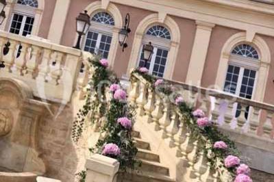 Miniature Location salle Préaux-Bocage (Calvados) - Domaine d'Aslan #10 Paysage rural avec un chemin en gravier, des champs de colza jaunes, des arbres et une terrasse en pierre au premier plan.