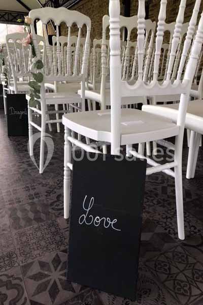 Chaises blanches alignées dans une salle avec un panneau noir portant l'inscription ’Love’ au premier plan.