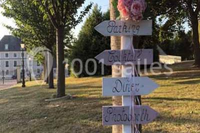 Miniature Location salle Préaux-Bocage (Calvados) - Domaine d'Aslan #12 Paysage rural avec un chemin en gravier, des champs de colza jaunes, des arbres et une terrasse en pierre au premier plan.