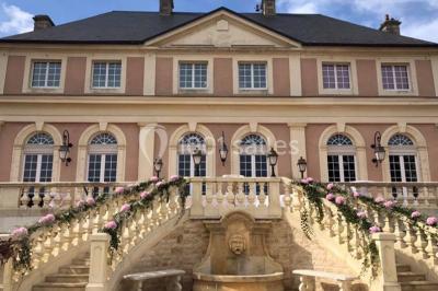 Miniature Location salle Préaux-Bocage (Calvados) - Domaine d'Aslan #9 Paysage rural avec un chemin en gravier, des champs de colza jaunes, des arbres et une terrasse en pierre au premier plan.
