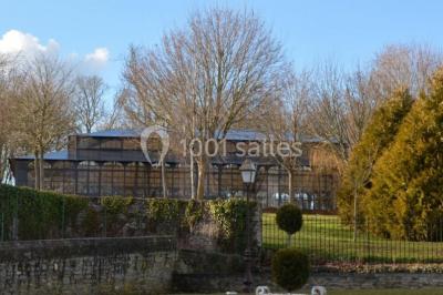 Chambre élégante avec lit double, lustre, murs décorés de papier peint sombre et vue sur un jardin par la fenêtre.
