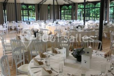 Chambre élégante avec lit double, lustre, murs décorés de papier peint sombre et vue sur un jardin par la fenêtre.