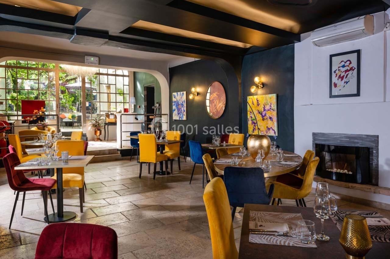 Salle de restaurant élégante avec des tables dressées, des chaises colorées et une décoration artistique moderne.