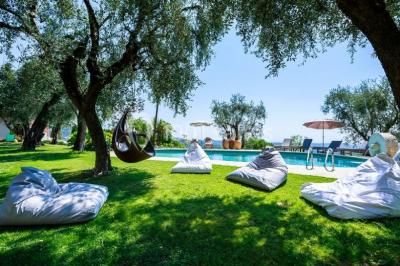 Massif de fleurs rouges et violettes entouré d'arbres et de verdure dans un jardin ensoleillé.