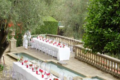 Massif de fleurs rouges et violettes entouré d'arbres et de verdure dans un jardin ensoleillé.
