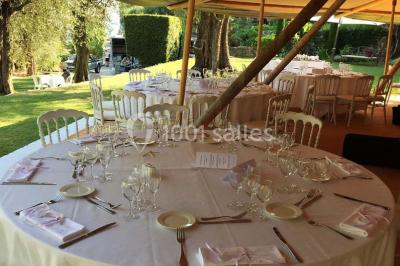 Massif de fleurs rouges et violettes entouré d'arbres et de verdure dans un jardin ensoleillé.