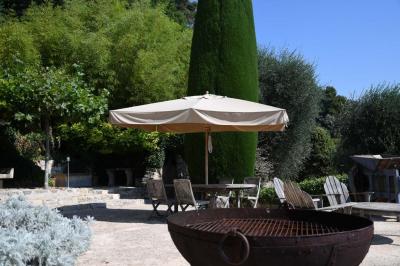 Massif de fleurs rouges et violettes entouré d'arbres et de verdure dans un jardin ensoleillé.