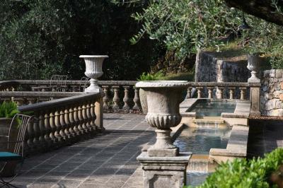 Massif de fleurs rouges et violettes entouré d'arbres et de verdure dans un jardin ensoleillé.