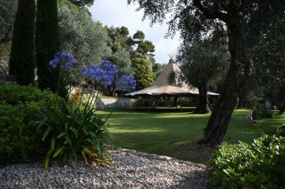 Massif de fleurs rouges et violettes entouré d'arbres et de verdure dans un jardin ensoleillé.