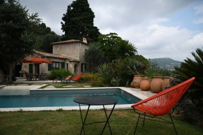 Massif de fleurs rouges et violettes entouré d'arbres et de verdure dans un jardin ensoleillé.