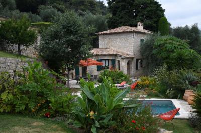 Massif de fleurs rouges et violettes entouré d'arbres et de verdure dans un jardin ensoleillé.