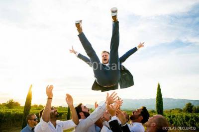 Allée bordée de cyprès et de vignes avec une vue sur une montagne en arrière-plan, sous un ciel clair.