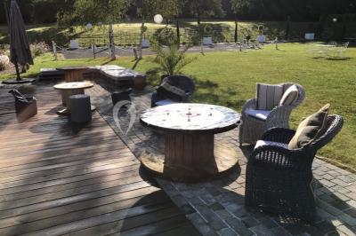 Centre de table floral avec fleurs séchées et pampas, entouré de couverts et cadeaux emballés sur une nappe blanche.