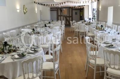 Centre de table floral avec fleurs séchées et pampas, entouré de couverts et cadeaux emballés sur une nappe blanche.