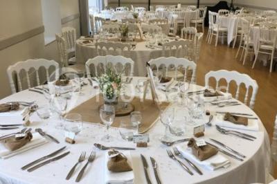 Centre de table floral avec fleurs séchées et pampas, entouré de couverts et cadeaux emballés sur une nappe blanche.