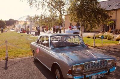 Centre de table floral avec fleurs séchées et pampas, entouré de couverts et cadeaux emballés sur une nappe blanche.