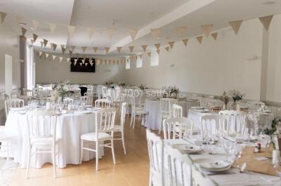 Centre de table floral avec fleurs séchées et pampas, entouré de couverts et cadeaux emballés sur une nappe blanche.